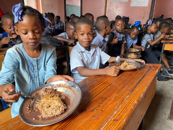 أطفال بالمرحلة الإبتدائية يتناولون وجبتهم الساخنة في فصولهم في مدرسة كاثرين فلون الحكومية في مدينة بهايتي. الصورة: برنامج الأغذية العالمي/ألكسيس ماسياريلي 