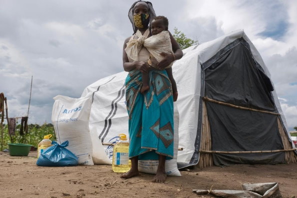 امرأة وطفلها يقفان أمام خيمة في مخيم لإعادة التوطين، كابو ديلجادو، موزمبيق. برنامج الأغذية العالمي/جرانت لي نوينبورغ