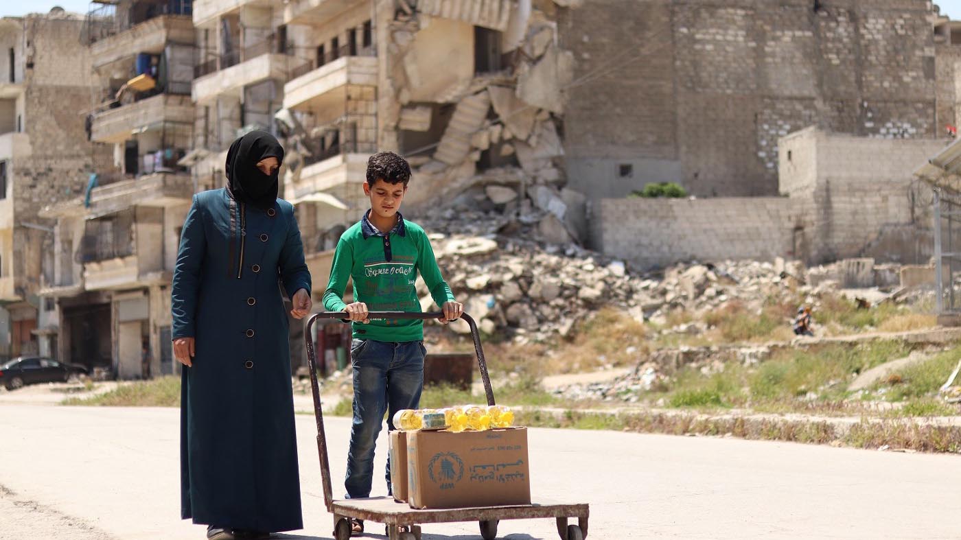 إحدى الأمهات وابنها ينقلان حصصاً غذائية من مقر برنامج الأغذية العالمي في حلب. الصورة: برنامج الأغذية العالمي/خضر اليسار