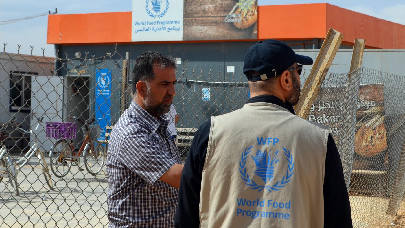 ناصر يتحدث إلى أحد اللاجئين في أحد المخبزين الموجودين في مخيم الزعتري للاجئين. تصوير: محمد عطيوي/ برنامج الأغذية العالمي