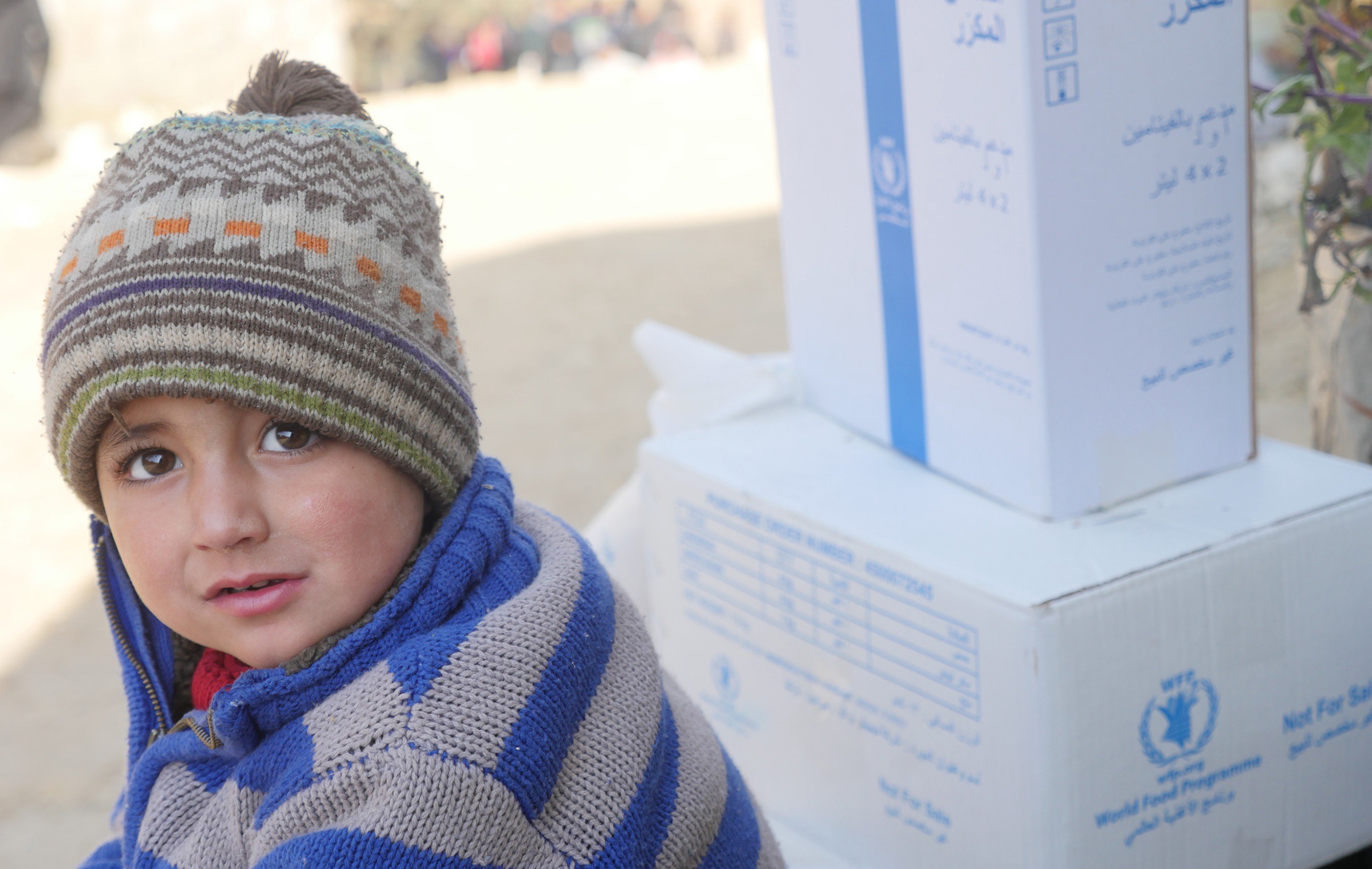 طفل نازح ينتظر عند نقطة توزيع المساعدات الغذائية في شمال سوريا. الصورة: برنامج الأغذية العالمي/جمعية ميرسي - الولايات المتحدة الأمريكية