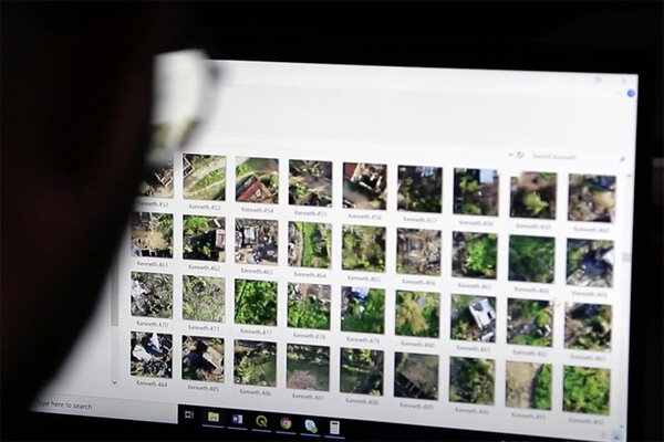 Silhouette of face looking at computer screen showing multiple small squared images of land