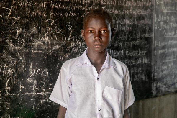 A teenage school student stands in front of a blackboard in South Sudan, Northern Bahr el Ghazal State. Photo: WFP/Eulalia Berlanga