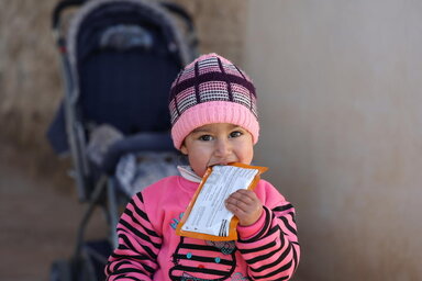WFP/ Hussam Al Saleh A two-year old Syrian girl eating a sachet of supplementary feeding butter.