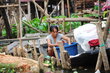 A woman in a boat in a flooded living area looks into a big, blue tub