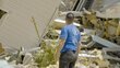 A man with a blue WFP T-shirt surveys damaged buildings. Photo: WFP/Gustavo Vera
