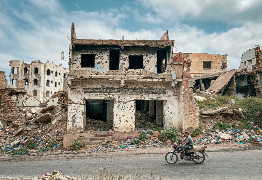 Man drives past building destroyed by conflict in Taz Yemen Feb 2020