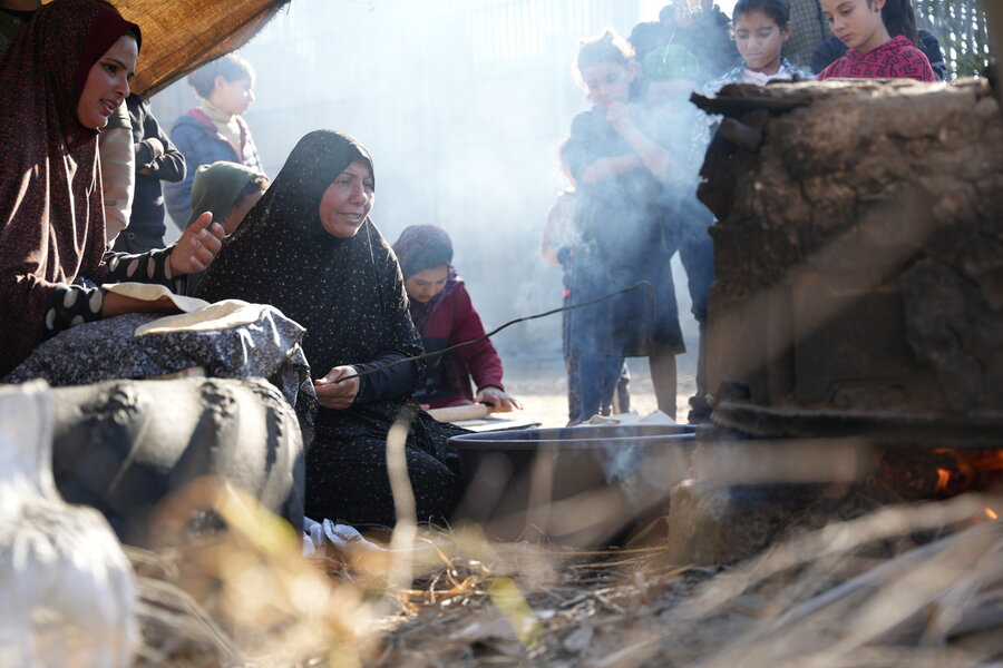 Um Ali cooks using a mud oven in a camp for displaced people in southern Gaza