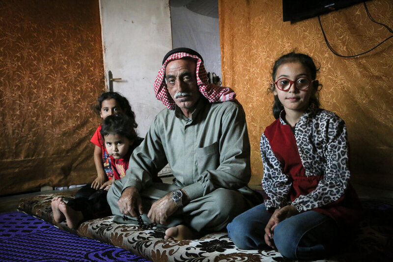 A father and his three daughters sit on the floor in a tent