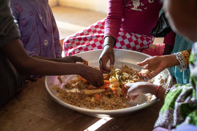 A group of hands taking food from a plate.