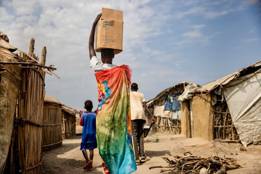 Carrying a box of WFP food assistance, Nyanene Gatdoor heads home to the displacement camp where she lives in South Sudan. She and her children count among thousands uprooted by devastating floods. Photo: WFP/Samantha Reinders