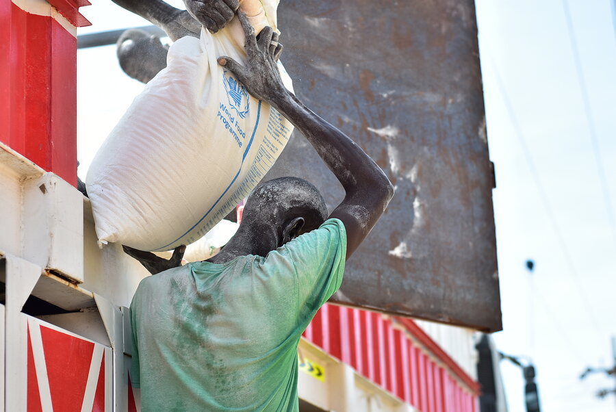 A man in a green T-shirt shoulders a bag of WFP food. Photo: WFP/Mohamed Galal