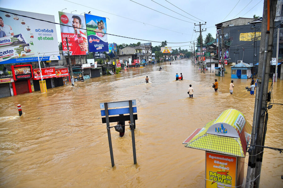 A wide road road, flooded, dotted with people immersed up to their knees