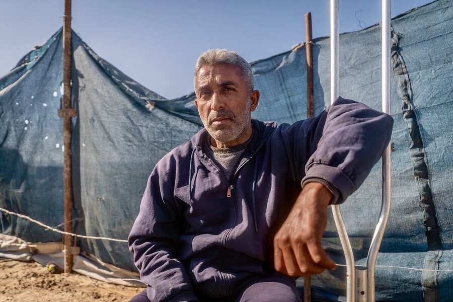 A man in a blue sweatshirt sits on dry ground, with a blue-cloth barrier in the background. Photo: WFP/Maxime Le Lijour