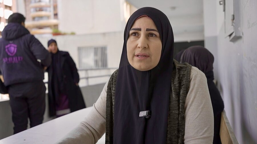 A woman in a dark headscarf and sad expression sits on a balcony. Photo: WFP/Khadija Dia