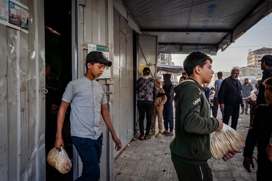 Young men walk out of a small bakery carrying plastic bags of flatbread. Photo: WFP/Maxime Le Lijour