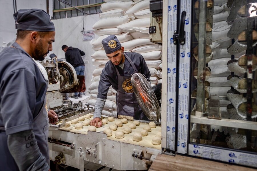 Commercial bakers in blue caps and jackets arrange balls of dough on a large tray. Photo: WFP/Maxime Le Lijour 
