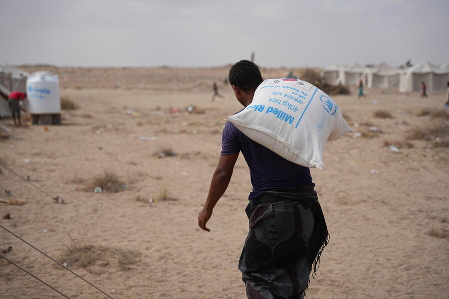  (Required) Displaced men collect sacks of fortified wheat flour and milled rice provided by the World Food Programme (WFP) at Al-Firdous Camp, Aden.