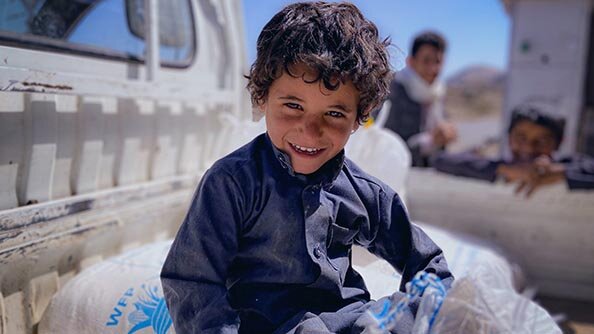 عمر البالغ من العمر أربع سنوات يجلس على أجولة الدقيق التي يوزعها برنامج الأغذية العالمي في خولان، اليمن. تصوير: برنامج الأغذية العالمي / محمد عوض