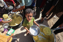 في الصورة، أطفال يتسلمون ويأكلون الأرز الذي حصلوا عليه من مطبخ للوجبات الساخنة مدعوم من برنامج الأغذية العالمي في المنطقة. ينتظر الأطفال لساعات بصبر للحصول على هذه الوجبة، وعادةً ما يأخذون الطعام إلى خيمة الأسرة. غزة، فلسطين. برنامج الأغذية العالمي/علي جدالله