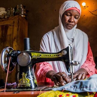 Maimuna sewing clothes at home, with the sewing machine given to her by WFP. Photo: WFP/Damilola Onafuwa