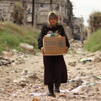 Woman carrying a box of food items.