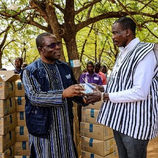 Aboubacar Koisha - WFP Country Director in Togo - hands over the cash and a package of fortified infant flour to Yoma Baka, Director General of the National Agency for Civil Protection (ANPC) during the launch of food assistance in Savanes and Kara regions in Togo. Photo: WFP/Richard Mbouet