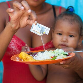 Mother fortifies her baby's food with Micronutrient Powder (MNP) "Sprinkles". Photo: WFP/Mike Bloem