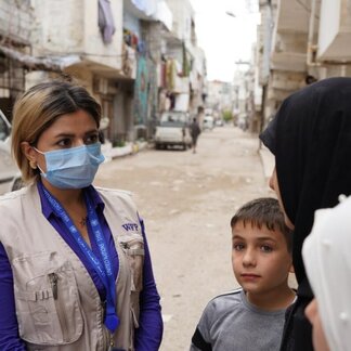 WFP staff talking with a woman beneficiary and her child